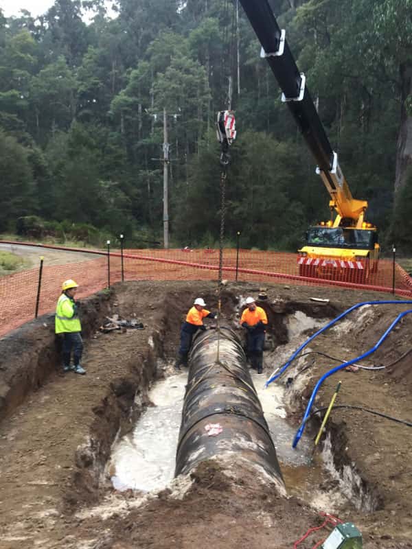 Workers and lifting equipment beside a pipeline