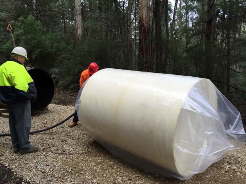 Workers handling wrapped pipeline equipment