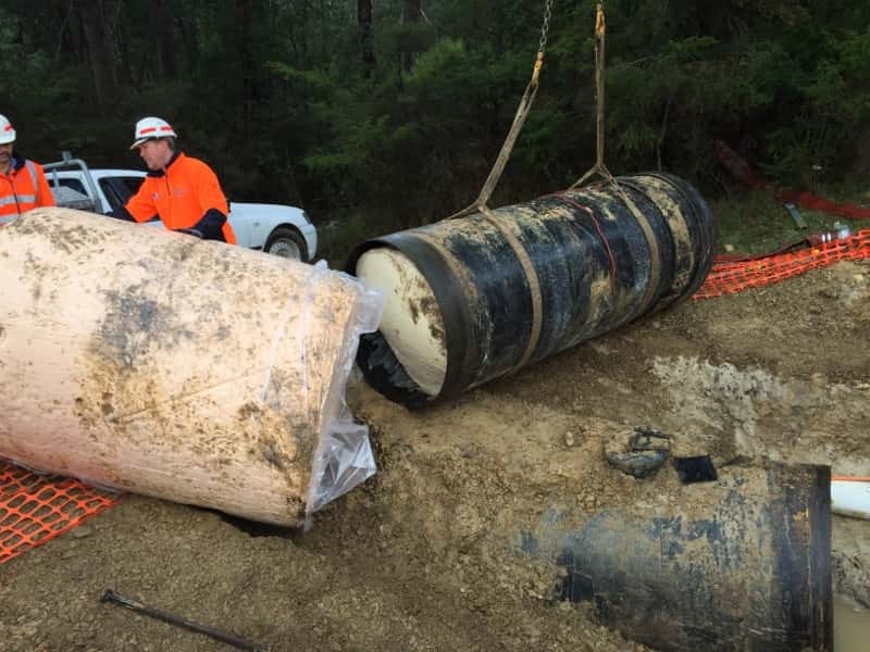 Workers handling a large pipe